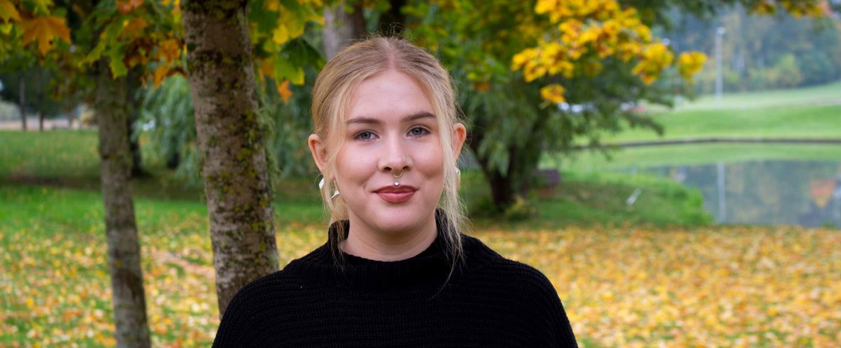 En kvinna står under ett träd och ler mot kameran.
