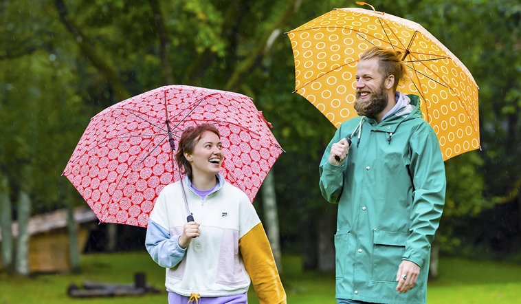 Två personer med paraplyer som skrattar